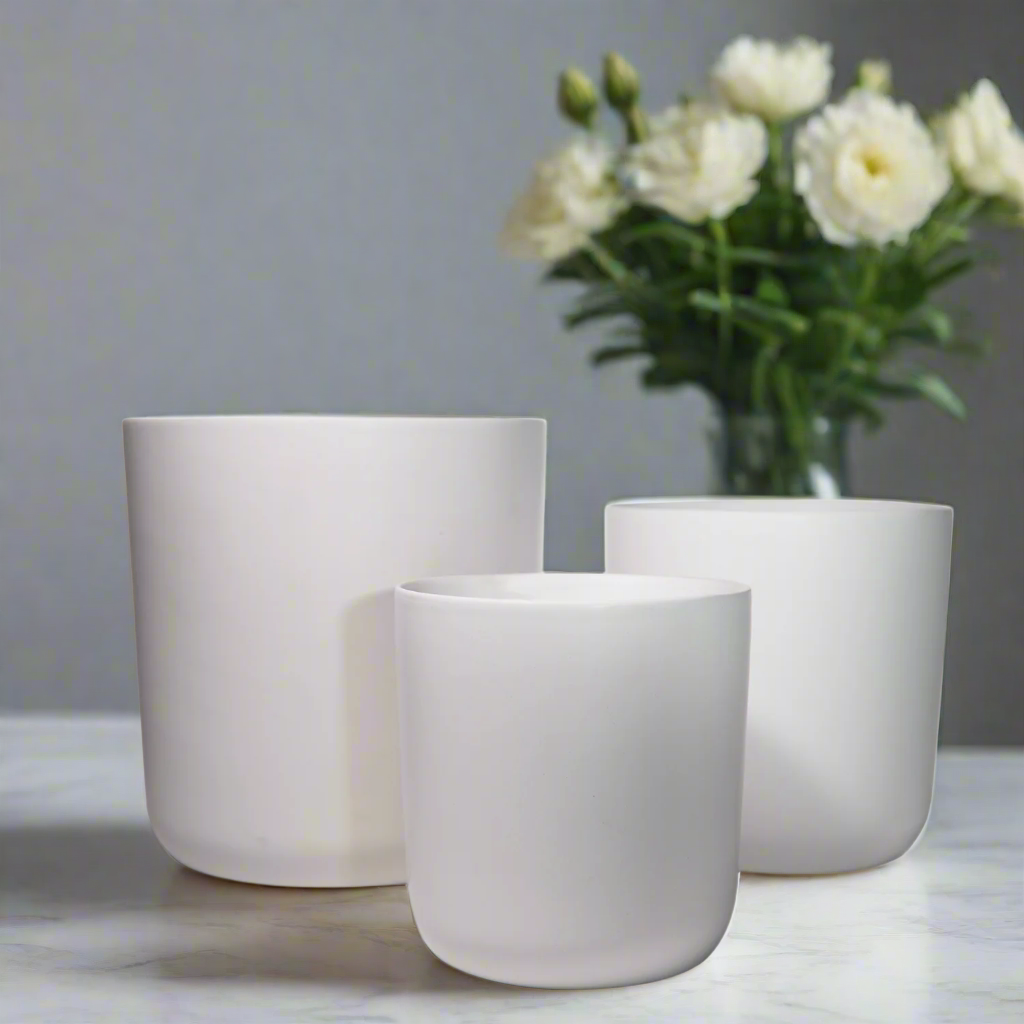 Three white ceramic pots on a marble surface with a blurred background of flowers.