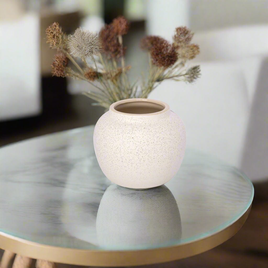 Textured ceramic vase with dried flowers on a glass table