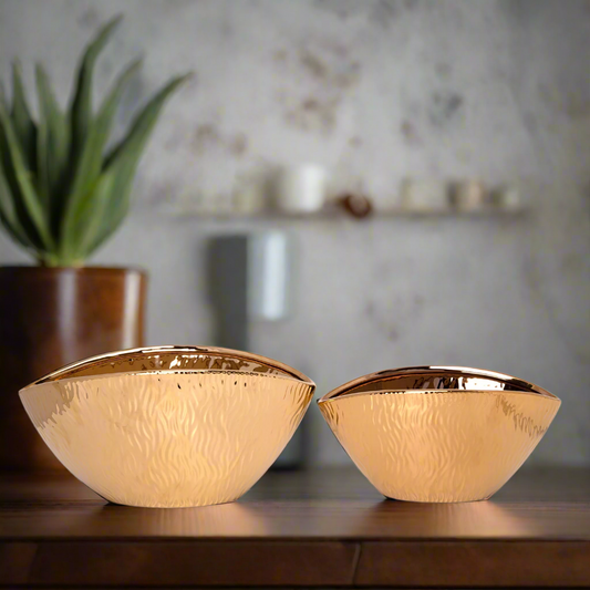 Two gold decorative bowls on a wooden surface with a blurred background